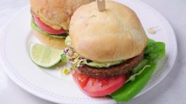 Avokado, domates ve fındık soslu vejetaryen burger, beyaz arka plan, dönen. 
