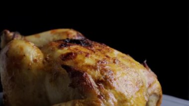 Pişmiş bütün tavuk siyah arka planda dönüyor..