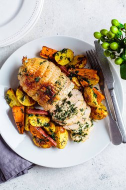 Kutlama masasında patates ve tatlı patates garnitürle servis edilen dolgulu tavuk göğsü. Noel tarifi konsepti.