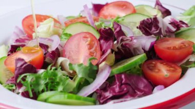 Taze sebze salatasına domates, salatalık ve soğanlı zeytin yağı dökülüyor. Yavaş çekim. 