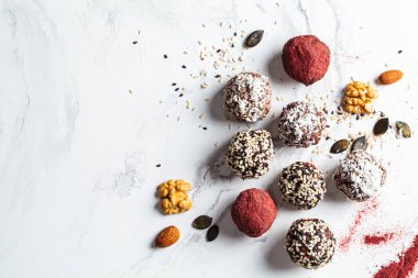 Raw vegan dessert. Energy balls. Truffles made from nuts, seeds, cocoa, dates and various superfood powders, flat lay, white marble background.