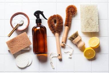 Eco home cleaning accessories. Natural brushes, sponges and organic cleaning products, flat lay on white tile background. Zero waste concept.