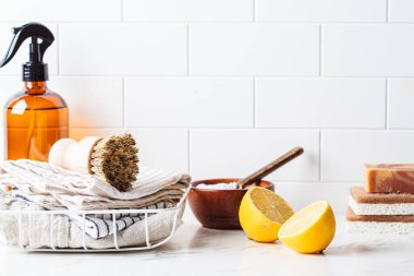 Eco home cleaning accessories. Natural brushes, sponges and organic cleaning products on white kitchen table, copy space. Zero waste concept.