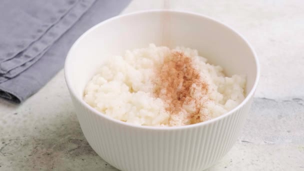 Scandinavian rice porridge with cinnamon and butter in white bowl. — 图库视频影像