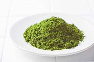 Beyaz tabakta kibrit yeşil çay tozu, kopyalama alanı. Geleneksel Japon içeceği.