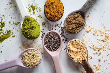 Kaşıklar içinde süper yiyecek tozları, beyaz mermer arka plan.