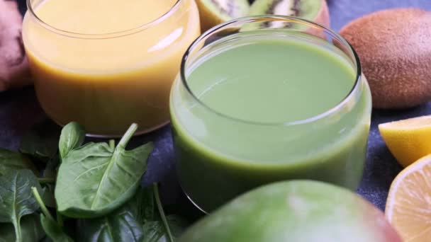 Gele mango smoothie en groene spinazie smoothie met ingrediënten op blauwe achtergrond. — Stockvideo