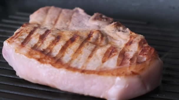 Cottura bistecca di maiale su padella nera. — Video Stock