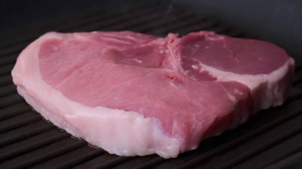 Vaření vepřového steaku na černé grilovací pánvi. — Stock video
