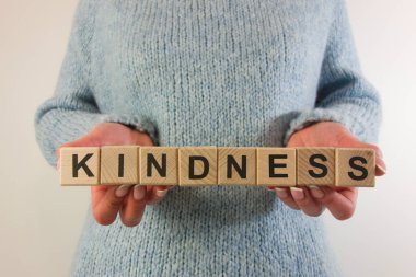 Ahşap bloklardan nezaket sözü tutan bir kadın. Dostluk ve iyi niyet kavramı