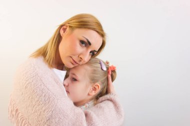 Beyaz arka planda küçük tatlı kızına sarılan bir kadın. Anneler Günü, ebeveynlik, aşk kavramları.