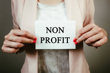 Kâr amacı gütmeyen bir kağıt parçası tutan bir iş kadını. İş, yardım, finansal konsept