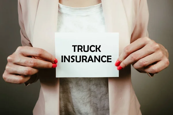 Female insurance agent holding sheet of paper with text truck insurance. Financial concept