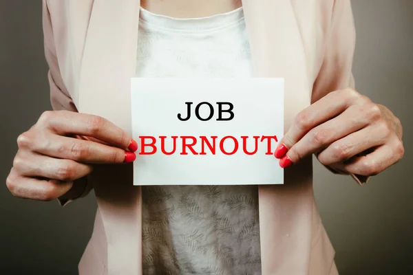 Female employee holding note with text job burnout. Leave employment, overworking, quitting work, exhaustion concept