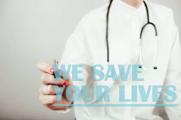 Female doctor writing text we save your lives. Healthcare, saving life, treatment and medical concept