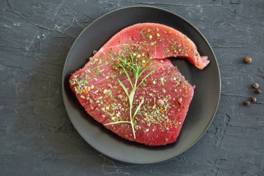 Fresh tuna steak on black concrete stone background. 
