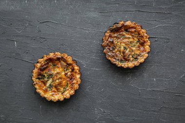 Tasty baked mini vegetable pie on black concrete background, top view.