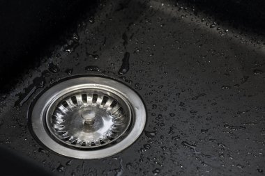 Matt, siyah mutfak lavabosu ve su damlalarıyla dolu metal drenaj.