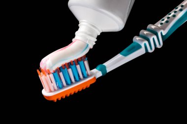 Beyaz plastik diş fırçası turuncu pedlerle, beyaz, mavi ve turuncu tüylerle siyah arkaplanda izole edilmiş renkli macun tüpleriyle