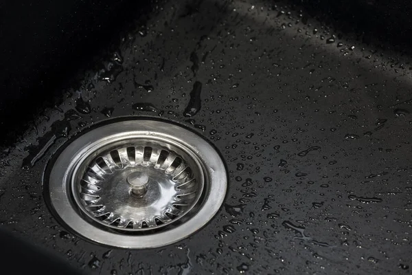 Matt, siyah mutfak lavabosu ve su damlalarıyla dolu metal drenaj.