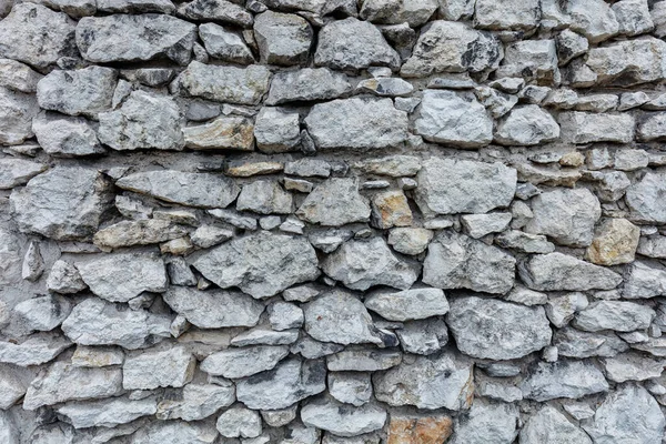 由不同尺寸和形状的灰色天然石头制成的古老的被毁坏的石墙 设计的背景 — 图库照片