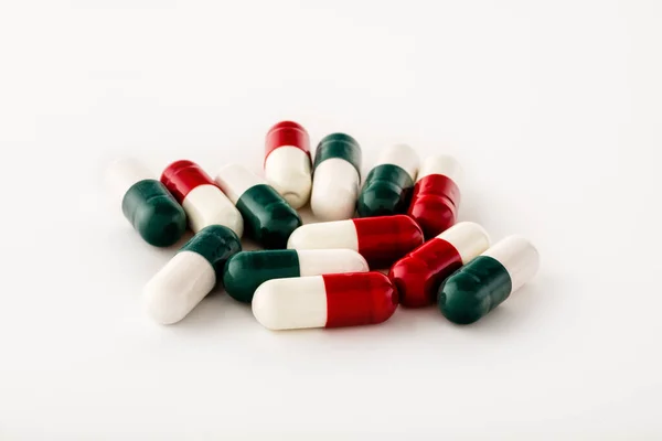 Kapsül biçimindeki çok renkli hapların bir kaç parçası beyaz arka planda izole bir şekilde yatmaktadır. Hızlı seçim için kırpma yolu var. Desing için.