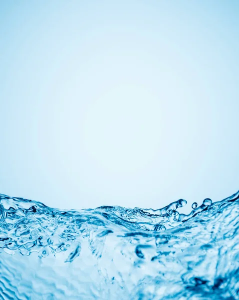 horizontally arranged splashes of clear water in the form of relief waves against a blue gradient background. Copy space.