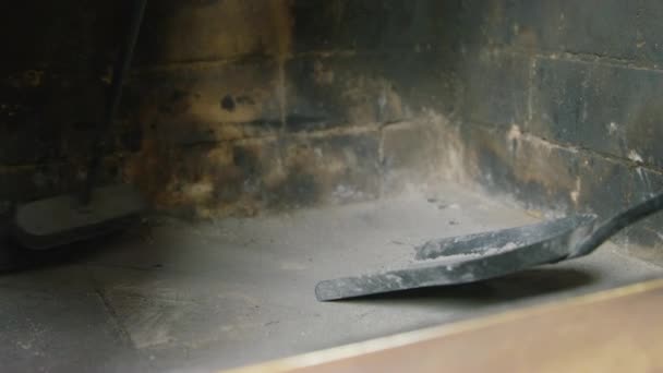 A pessoa com a ajuda da panela de pó e uma vassoura termina de reunir cinzas e cinzas da lenha depois que queimaram por, perto. Limpeza da lareira após a utilização — Vídeo de Stock