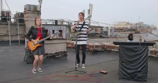 06 вересня 2021 року, Санкт-Петербург, Росія: Teenage rock band поставив концерт на даху. Парень и девочка стрибают с электрическими гітарами, песят с микрофоном, а забавный пес в шляпе играет в синтезатор — стокове відео