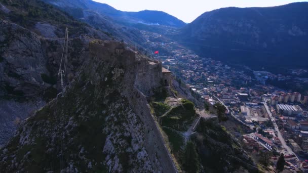 Old fortress on steep mountain top against town in valley — Stock Video