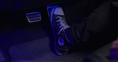Kanvas ayakkabılı sürücü, araba karanlık salonunda gaz pedalına basıyor.
