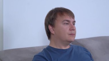Komik adam pirinç zili çalıp gri koltukta yemek istiyor.