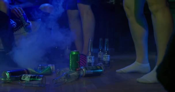 Septiembre 06 2021, San Petersburgo, Rusia: La fiesta está en pleno apogeo - botellas de cerveza y latas están tumbados en el suelo, la gente está bailando, vapor del generador de niebla está girando a su alrededor, vista de bajo ángulo — Vídeo de stock