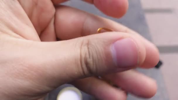 A mão da pessoa gira a cápsula líquida amarela clara nos dedos — Vídeo de Stock