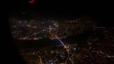 Aydınlatılmış gece kenti ve nehir uçak penceresi