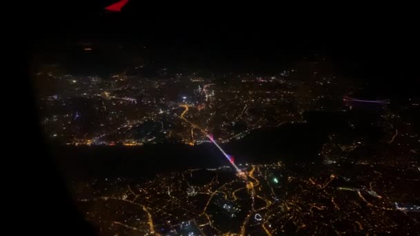Cidade noturna iluminada com rio fora da janela do avião — Vídeo de Stock