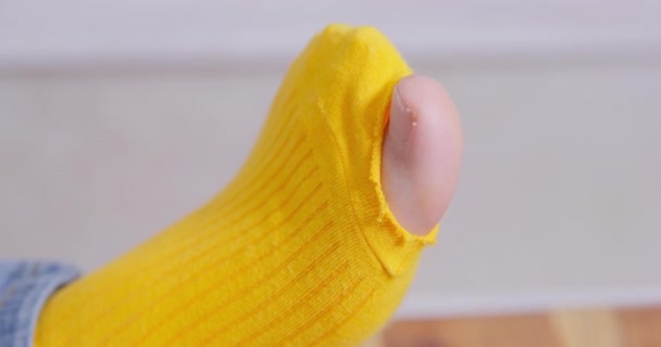 Слоб намагається сховати дірку на жовтій шкарпетці, з якої ганебно стирчить палець. Особа не дбає про свій зовнішній вигляд або не має грошей на новий одяг. — стокове відео