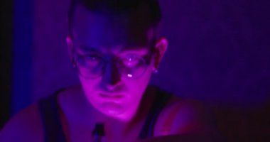 Gözlüklü, kulağına piercing takan ve elektronik sigaradan yavaşça buhar çıkaran şık bir genç. Odadaki bastırılmış ışık renkleri sorunsuzca değiştiriyor, mistik atmosfer yaratıyor.