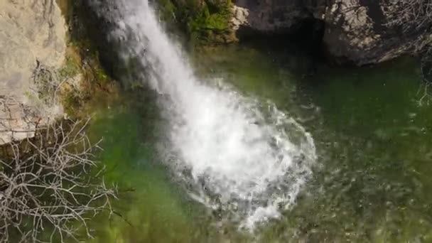Wit schuimend water valt in rustig meer van grote bruine rotsachtige klif met mos ON stenen onder fel zonlicht vanuit de lucht — Stockvideo