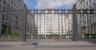 Bir çift dachshund köpeği okul binasının çitlerinden koşuyor.