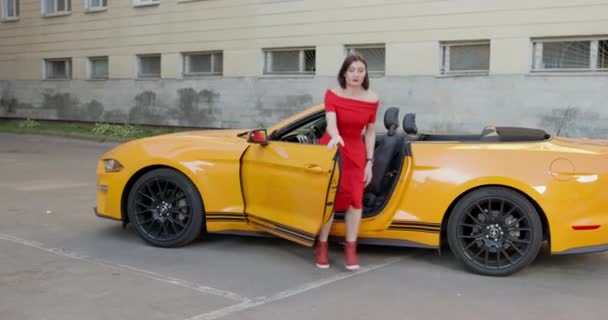 06 septembre 2021, Saint-Pétersbourg, Russie : femme avec un maquillage spectaculaire sort de voiture convertible, trouve soudainement quelque chose sur le sol et pointe à la main tout en marchant dans le parking — Video