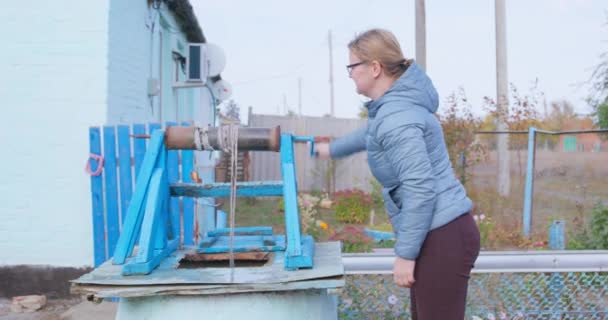 Curvy woman gets water from old draw-well in village yard — Stock Video