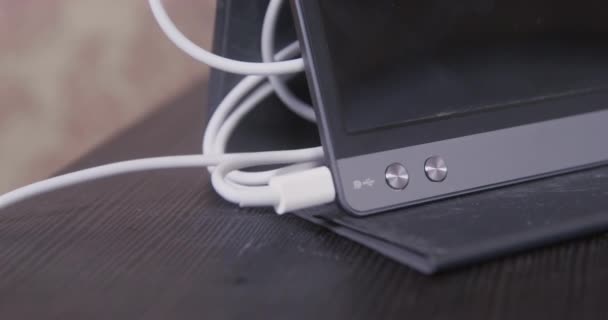 Le fil du chargeur démêle et traîne la tablette debout sur la table — Video