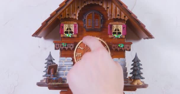 Палець людини налаштовує старовинний будинок у формі настінного годинника для сигналу — стокове відео