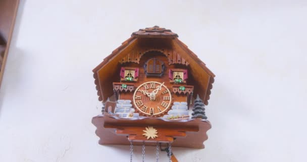 Wooden house-shaped wall clock with pendulum on white wall — Video Stock