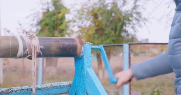 Кривая женщина получает воду из старого деревянного колодца в сельской местности — стоковое видео