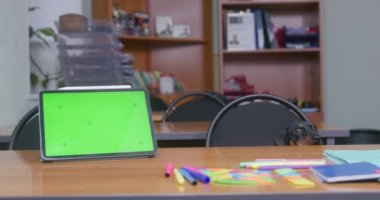 Dachshund sits at desk near tablet PC with chromakey