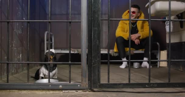 Dachshund i mężczyzna w żółtym futrze siedzą razem w klatce — Wideo stockowe