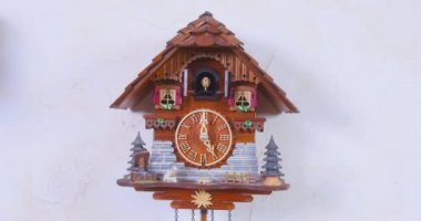 Klasik otantik ahşap guguklu saat sesi ve her notayla hareket eden otomatik guguk kuşu ile saatleri vuruyor, evdeki duvarda asılı, ön manzara