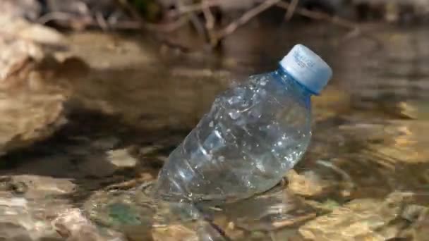 Puste używane plastikowe butelki pływa wzdłuż czystej wody górskiego jeziora z skalistych brzegów na miły słoneczny dzień. Problem ekologiczny — Wideo stockowe